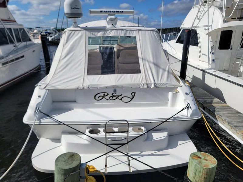 Slide: The Image of 1997 Sea Ray 400 Express Cruiser docked at marina, rear view with canopy and name "R&J". - 4