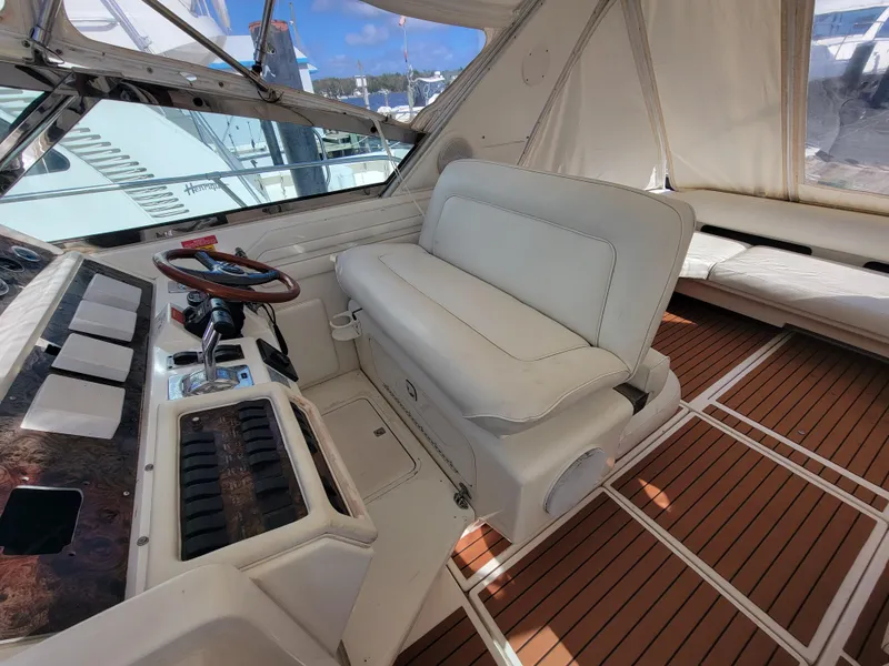 Slide: The Image of 1997 Sea Ray 400 Express Cruiser cockpit with white seating and wood flooring. - 7