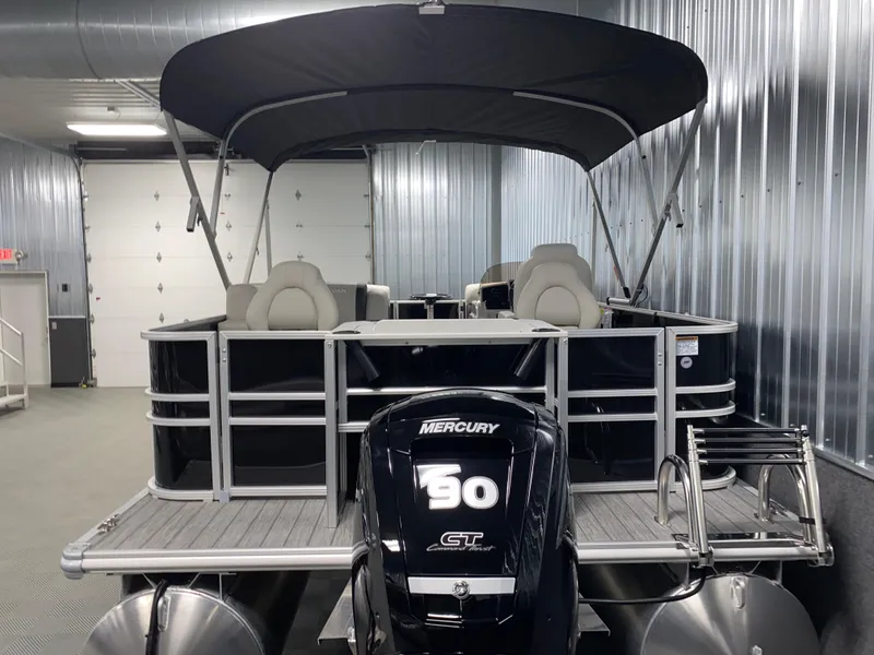 Slide: The Image of 2025 Sylvan Mirage 8520 Party Fish pontoon with Mercury 90HP engine in a metal-walled showroom. - 23