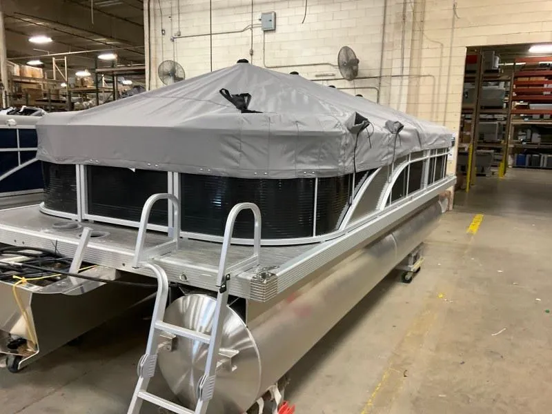 Slide: The Image of 2023 Bennington 21SSR pontoon boat with cover in a warehouse setting. - 2