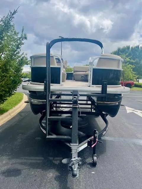 Slide: The Image of 2025 Sun Tracker Party Barge 16 DLX on trailer, parked outdoors under cloudy sky. - 2