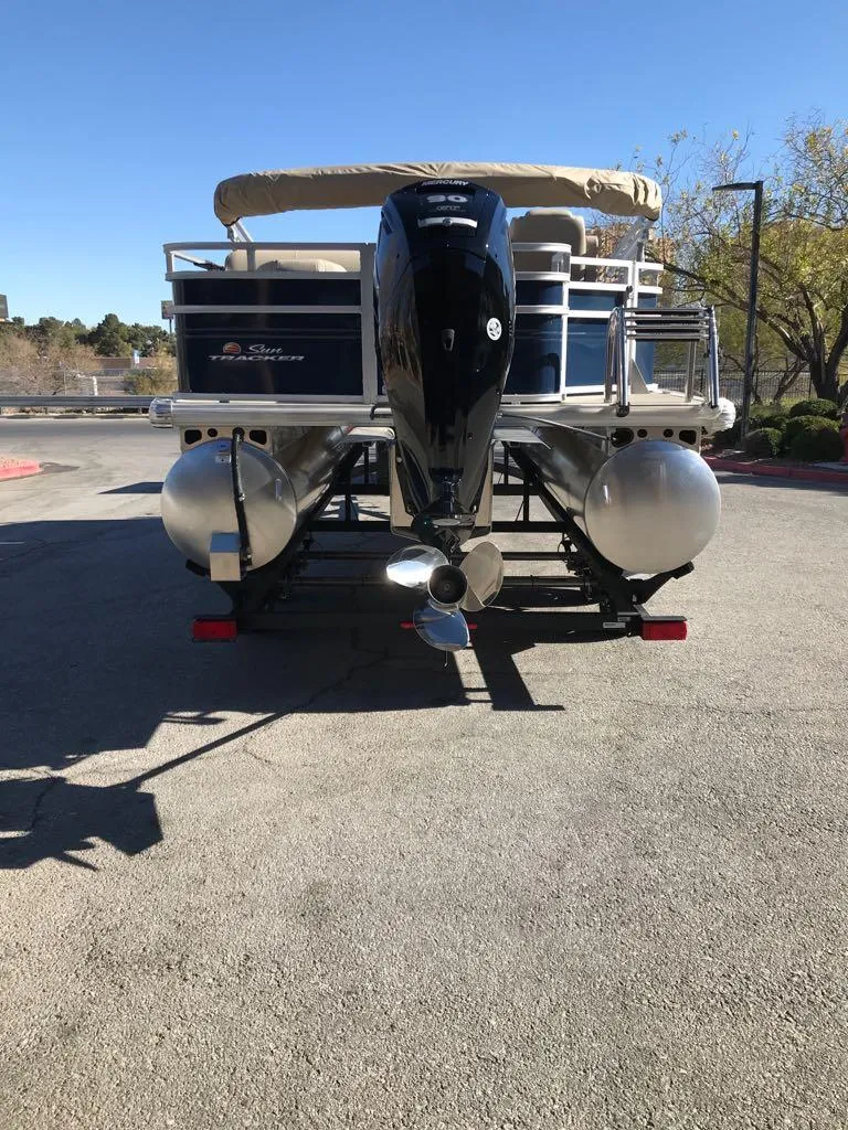 Slide: The Image of 2025 Sun Tracker Fishin' Barge 20 DLX pontoon boat, rear view, parked outdoors. - 10