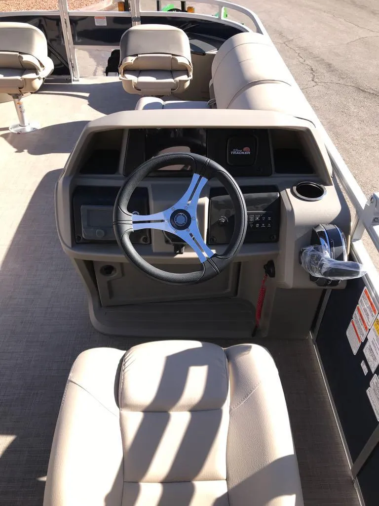 Slide: The Image of 2025 Sun Tracker Fishin' Barge 20 DLX boat interior with steering wheel and seating. - 11