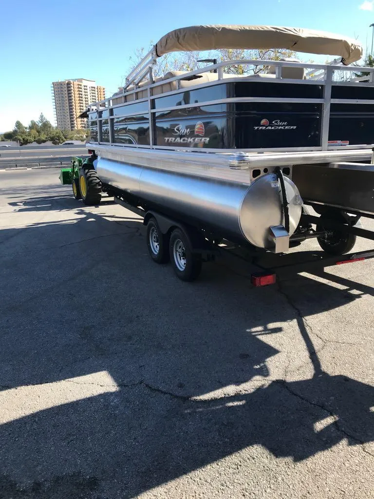 Slide: The Image of 2025 Sun Tracker Fishin' Barge 20 DLX pontoon boat on trailer in parking lot. - 4