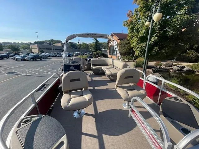 Slide: The Image of 2025 Sun Tracker Bass Buggy 18 DLX pontoon boat with beige seating in a parking lot. - 2