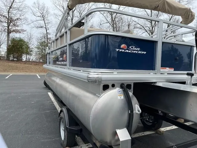 Slide: The Image of 2025 Sun Tracker Bass Buggy 18 DLX pontoon boat in parking lot. - 2