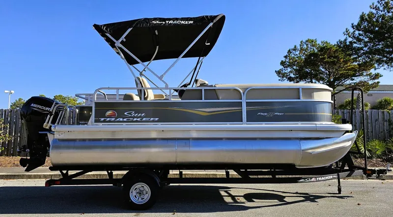 The Image of 2025 Sun Tracker Party Barge 18 DLX pontoon boat on trailer, parked outdoors. - 0