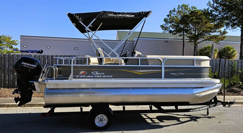 Slide: The Image of 2025 Sun Tracker Party Barge 18 DLX pontoon boat on trailer, parked outdoors. - 8
