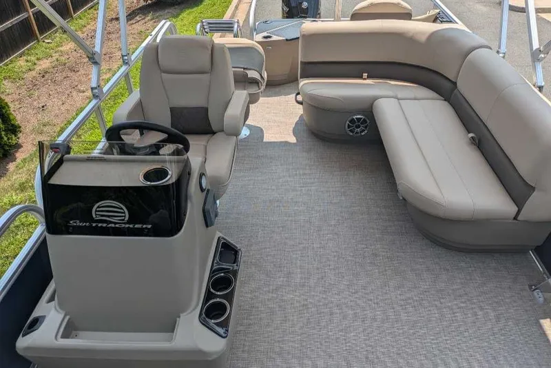 Slide: The Image of 2025 Sun Tracker Bass Buggy 18 DLX pontoon boat interior with beige seating and steering console. - 4