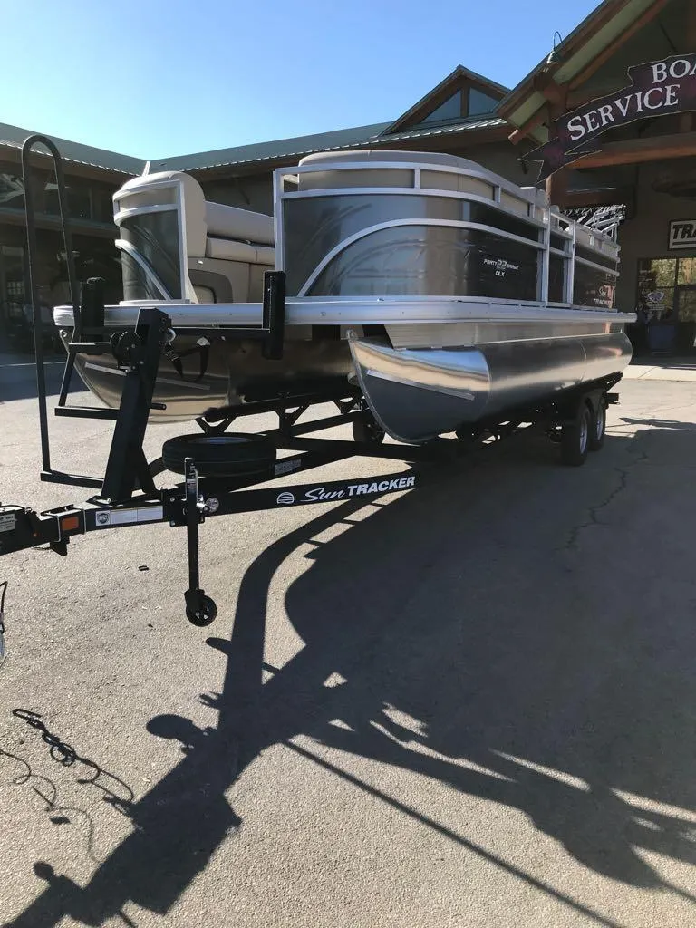 Slide: The Image of 2025 Sun Tracker Party Barge 22 DLX pontoon boat on trailer outside service center. - 5
