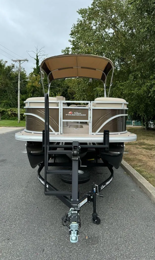 Slide: The Image of 2025 Sun Tracker SportFish 22 XP3 pontoon boat on trailer, parked on a road. - 3