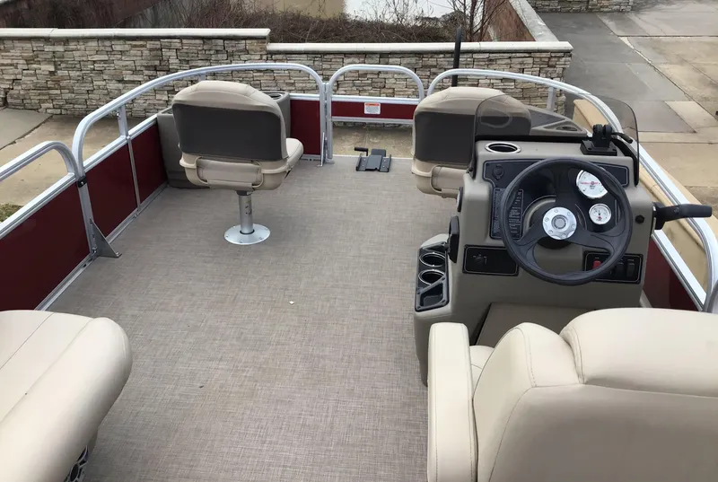 Slide: The Image of 2025 Sun Tracker Bass Buggy 18 DLX pontoon boat interior with beige seating and steering console. - 2