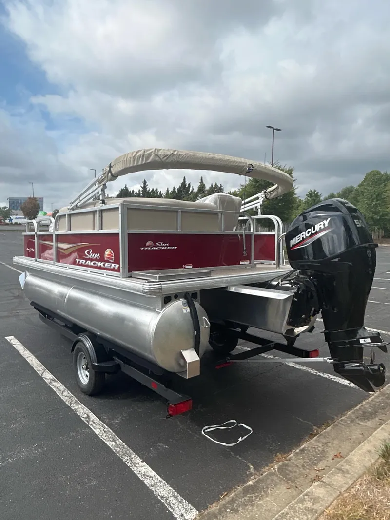 Slide: The Image of 2025 Sun Tracker Bass Buggy 16 XL Select pontoon boat with Mercury engine in parking lot. - 3