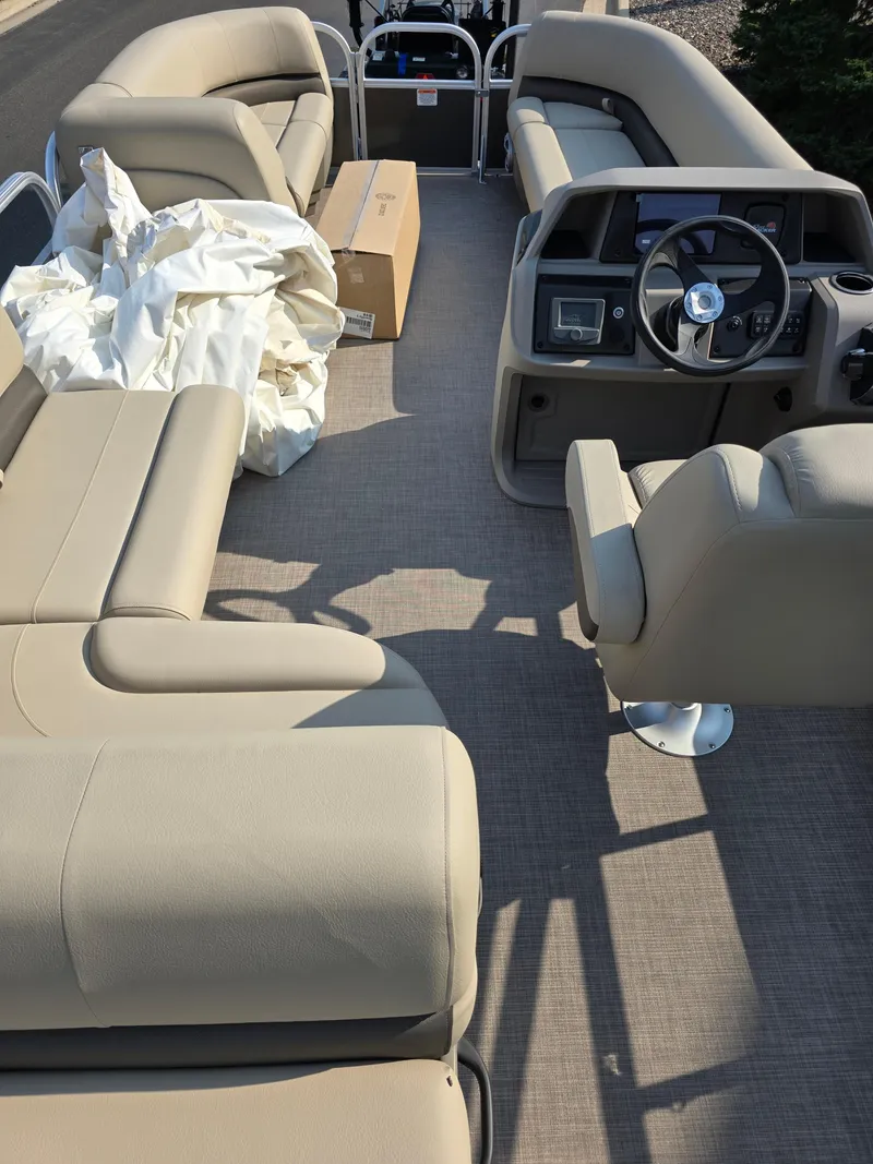 Slide: The Image of 2025 Sun Tracker Party Barge 18 DLX interior with beige seating and steering console. - 4
