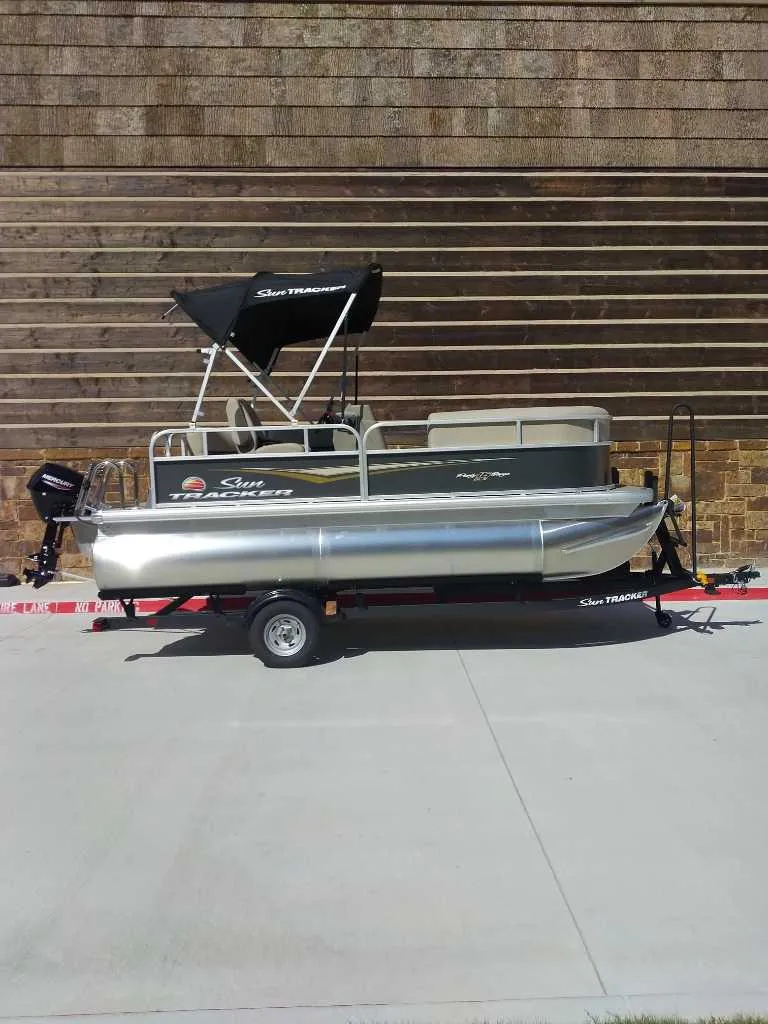 Slide: The Image of 2025 Sun Tracker Party Barge 16 DLX pontoon boat on trailer, side view. - 1