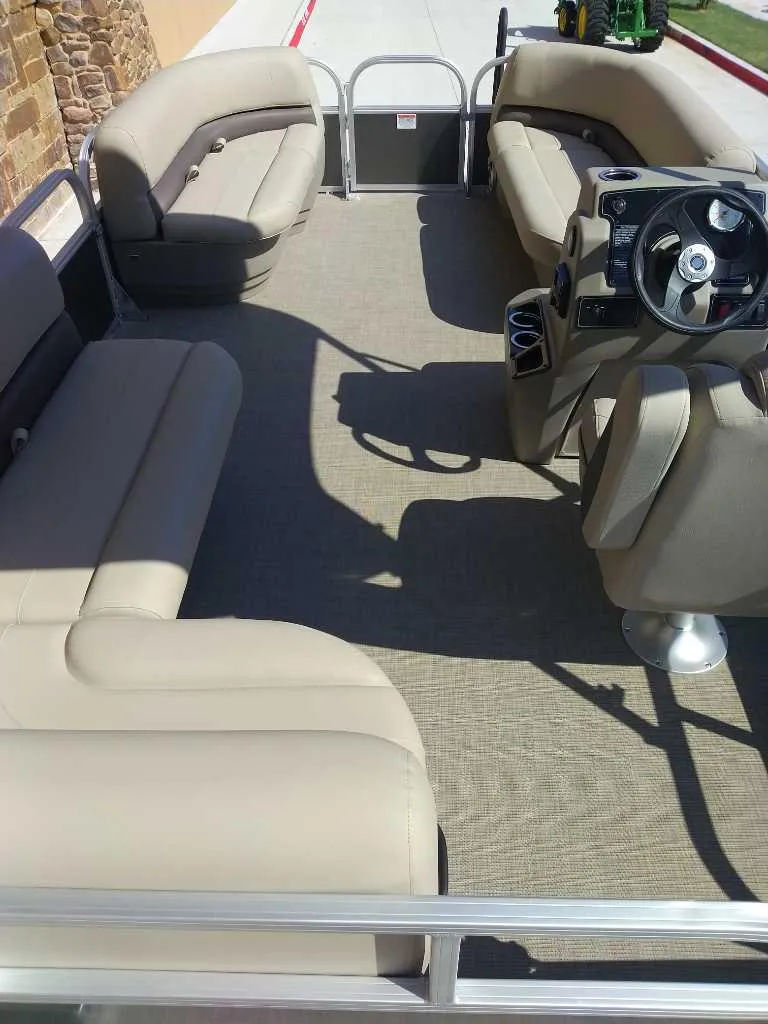 Slide: The Image of 2025 Sun Tracker Party Barge 16 DLX interior with beige seating and steering console. - 7
