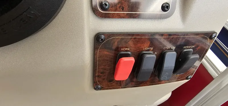 Slide: The Image of Control panel of 2025 Sun Tracker Bass Buggy 18 DLX with switches for horn, lights, and aerator. - 12