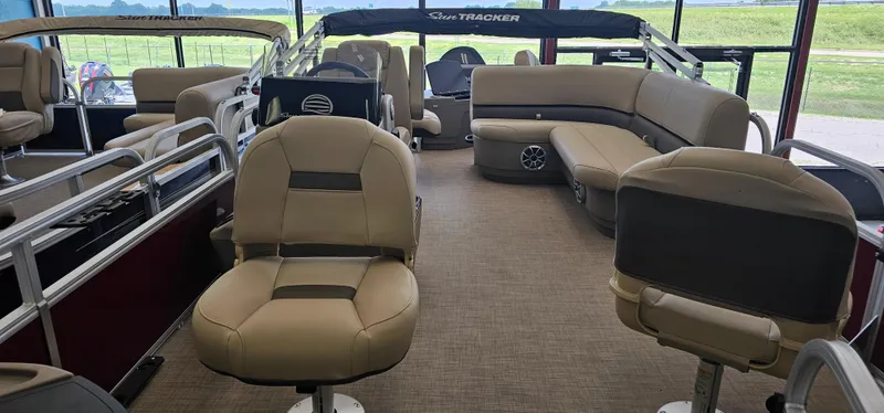 Slide: The Image of 2025 Sun Tracker Bass Buggy 18 DLX pontoon boat interior with beige seating and spacious layout. - 2