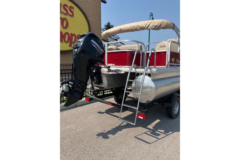 Slide: The Image of 2025 Sun Tracker Bass Buggy 18 DLX pontoon boat with Mercury engine, parked outdoors. - 5