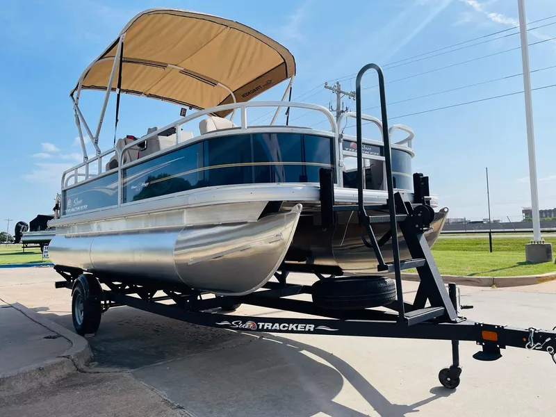 Slide: The Image of 2025 Sun Tracker Bass Buggy 18 DLX pontoon boat on trailer, sunny day. - 3