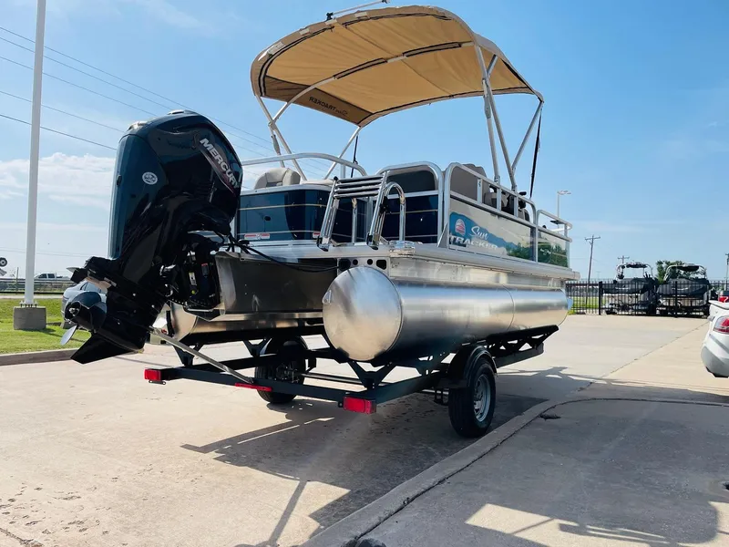Slide: The Image of 2025 Sun Tracker Bass Buggy 18 DLX pontoon boat on trailer, parked outdoors. - 5