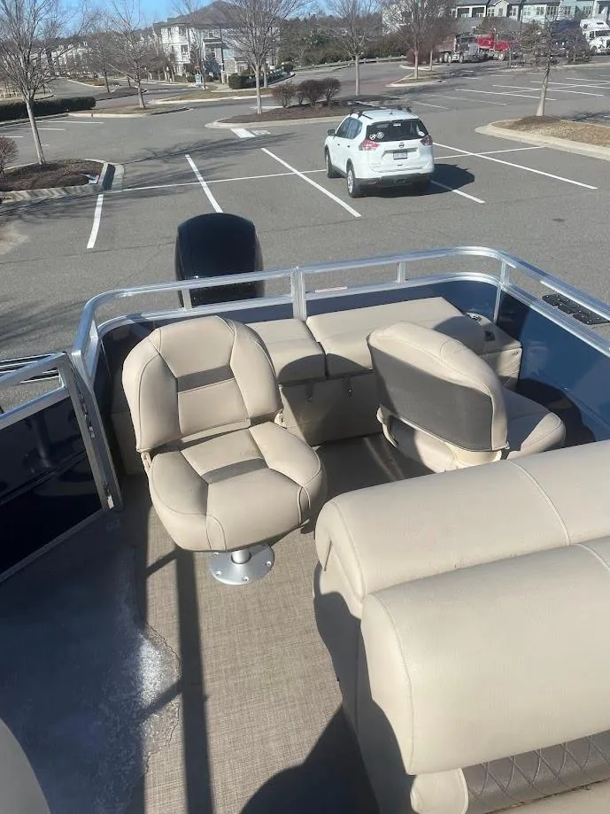 Slide: The Image of 2025 Sun Tracker Fishin' Barge 22 DLX with beige seating in a parking lot. - 2