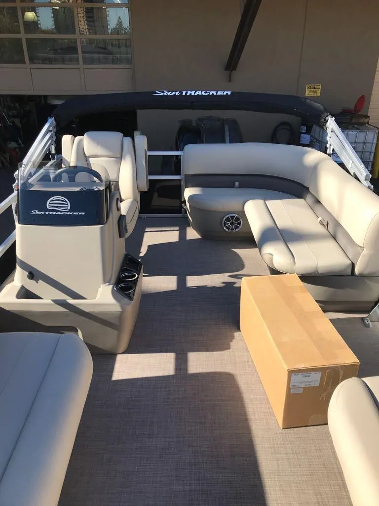Slide: The Image of 2025 Sun Tracker Party Barge 16 DLX interior with beige seating and helm. - 11