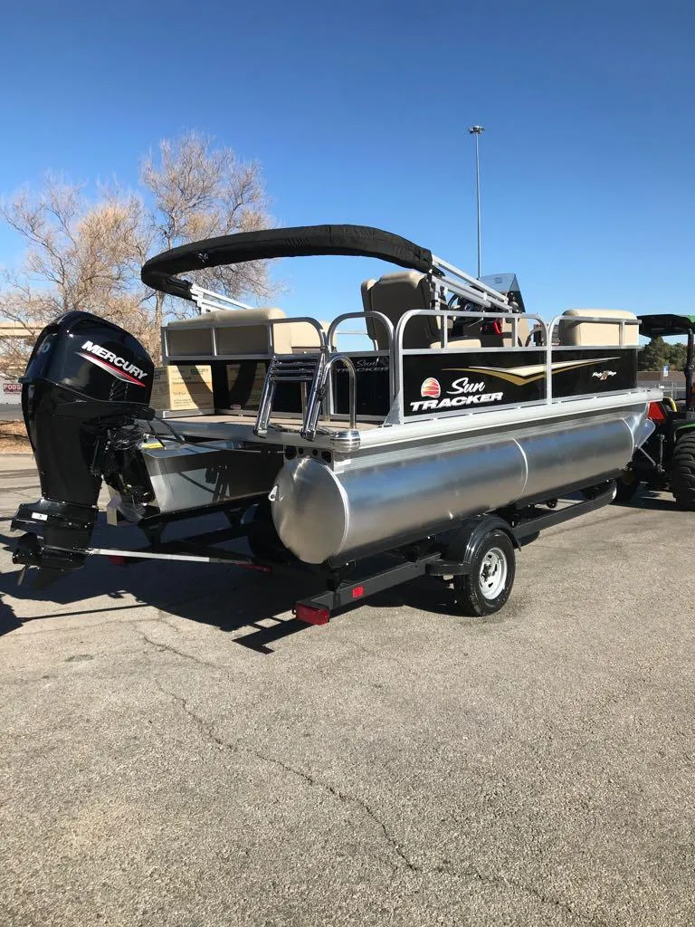 Slide: The Image of 2025 Sun Tracker Party Barge 16 DLX pontoon boat with Mercury engine, parked outdoors. - 5