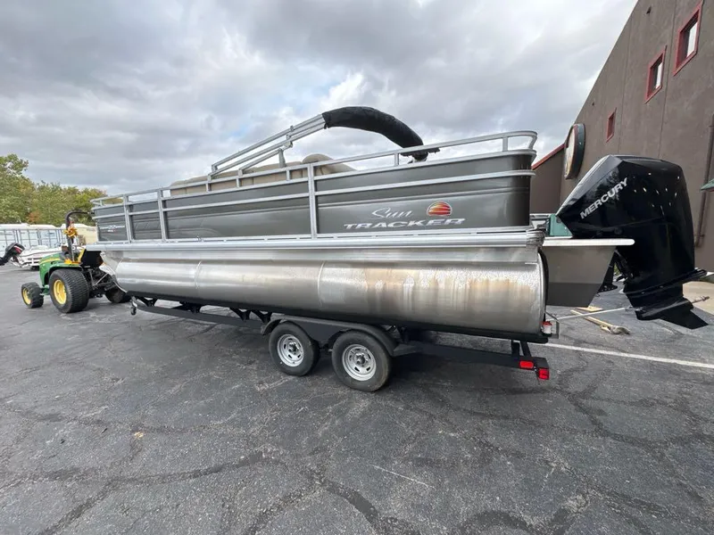 Slide: The Image of 2025 Sun Tracker Fishin' Barge 22 XP3 pontoon boat on trailer, parked outdoors. - 3