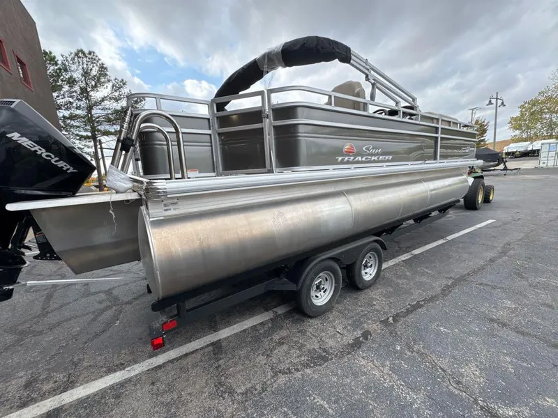 Slide: The Image of 2025 Sun Tracker Fishin' Barge 22 XP3 pontoon boat on trailer in parking lot. - 4