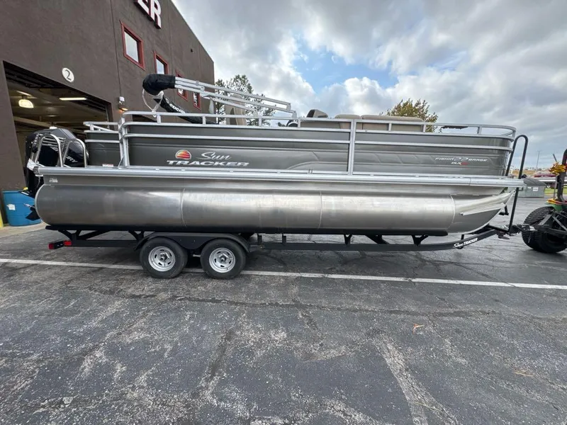 Slide: The Image of 2025 Sun Tracker Fishin' Barge 22 XP3 pontoon boat on trailer, parked outdoors. - 5