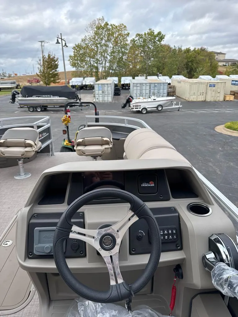 Slide: The Image of 2025 Sun Tracker Fishin' Barge 22 XP3 dashboard and steering wheel, outdoor setting. - 8