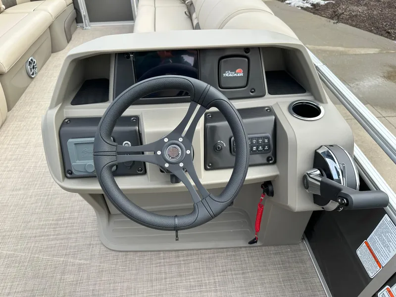 Slide: The Image of 2025 Sun Tracker Party Barge 24 DLX steering console with modern controls and beige upholstery. - 6
