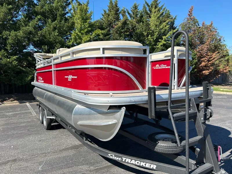 Slide: The Image of 2025 Sun Tracker Party Barge 22 RF DLX pontoon boat on trailer, parked outdoors. - 3