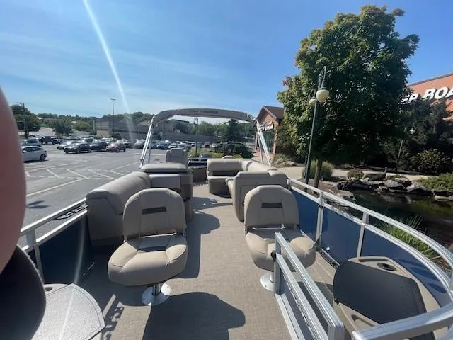 Slide: The Image of 2025 Sun Tracker Fishin' Barge 20 DLX pontoon boat with spacious seating in a sunny parking lot. - 2