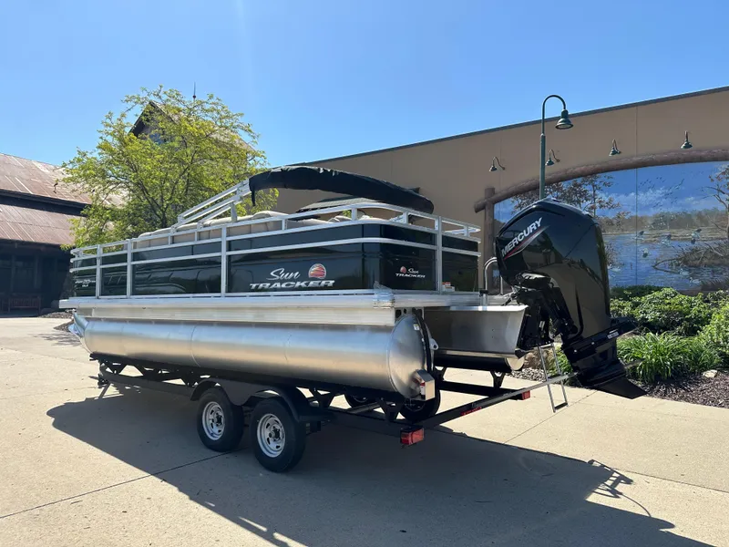 Slide: The Image of 2025 Sun Tracker SportFish 20 DLX pontoon boat on trailer, outdoor setting. - 2