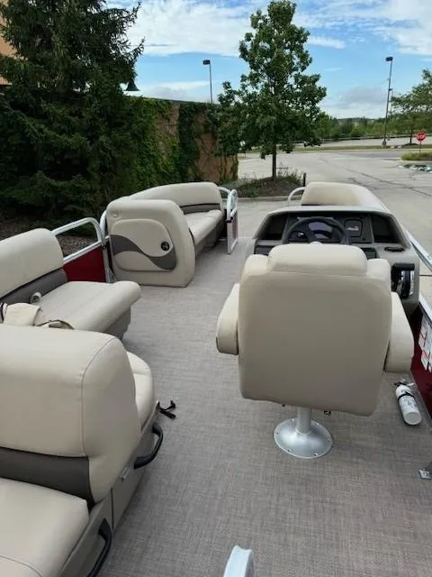 Slide: The Image of 2025 Sun Tracker Party Barge 18 DLX interior with beige seating and steering console. - 2