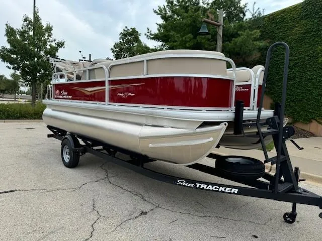 Slide: The Image of 2025 Sun Tracker Party Barge 18 DLX pontoon boat on trailer, parked outdoors. - 3