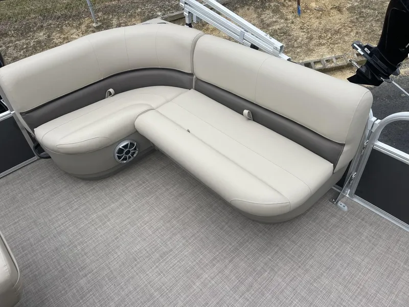 Slide: The Image of 2025 Sun Tracker Party Barge 16 DLX interior seating with beige upholstery and speaker. - 10