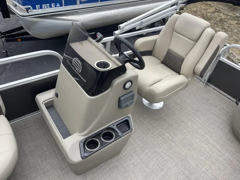 Slide: The Image of 2025 Sun Tracker Party Barge 16 DLX helm with beige seating and steering console. - 11