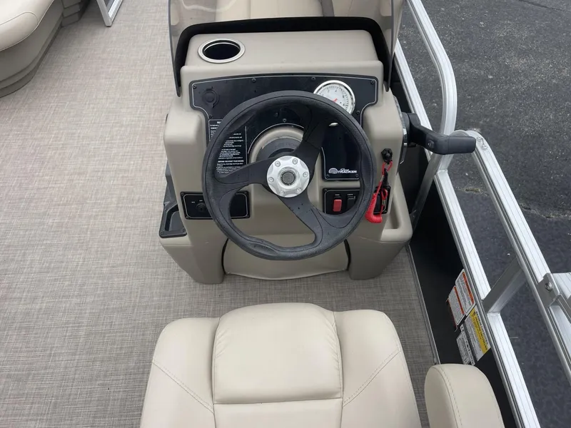 Slide: The Image of 2025 Sun Tracker Party Barge 16 DLX steering console with beige seating and controls. - 13