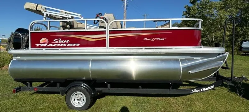 Slide: The Image of 2025 Sun Tracker Bass Buggy 16 XL Select pontoon boat on trailer, side view. - 2