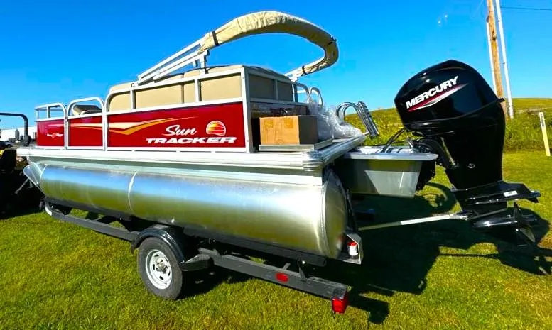 Slide: The Image of 2025 Sun Tracker Bass Buggy 16 XL Select pontoon boat with Mercury engine on grassy field. - 3