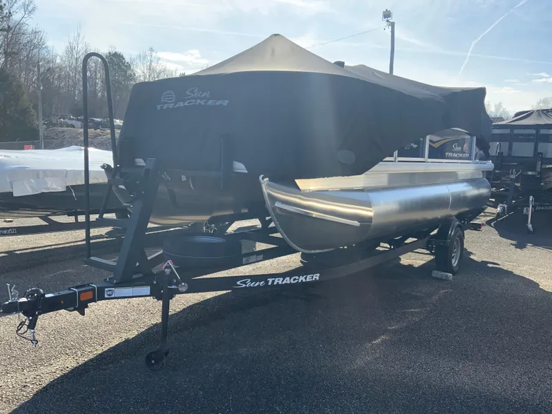 Slide: The Image of 2025 Sun Tracker Bass Buggy 18 DLX pontoon boat on trailer, covered and parked outdoors. - 10