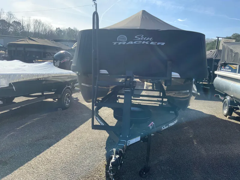 Slide: The Image of 2025 Sun Tracker Bass Buggy 18 DLX pontoon boat on trailer, covered and parked outdoors. - 11