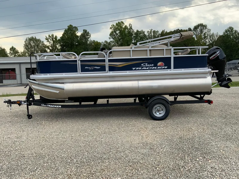 Slide: The Image of 2025 Sun Tracker Bass Buggy 18 DLX pontoon boat on trailer, parked outdoors. - 3