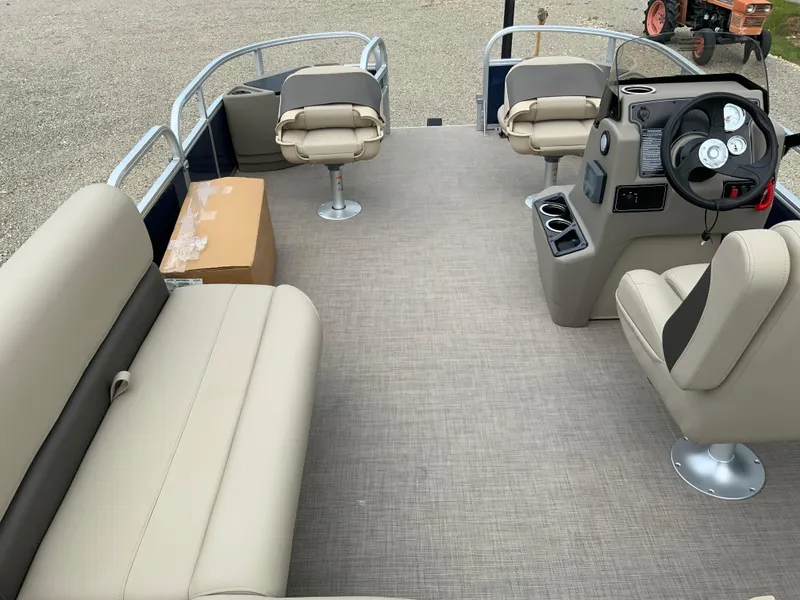 Slide: The Image of 2025 Sun Tracker Bass Buggy 18 DLX pontoon boat interior with beige seating and steering console. - 6