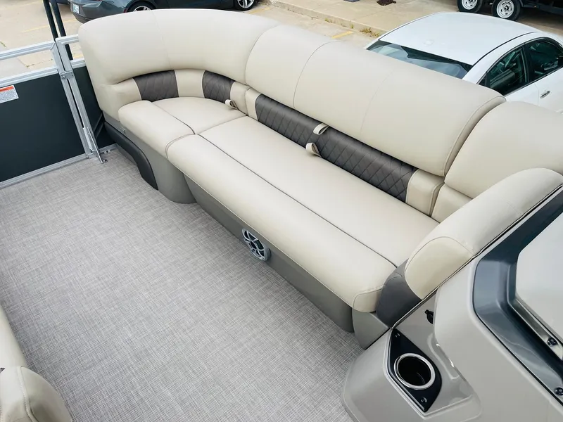 Slide: The Image of 2025 Sun Tracker Party Barge 20 DLX interior with beige seating and cup holders. - 13