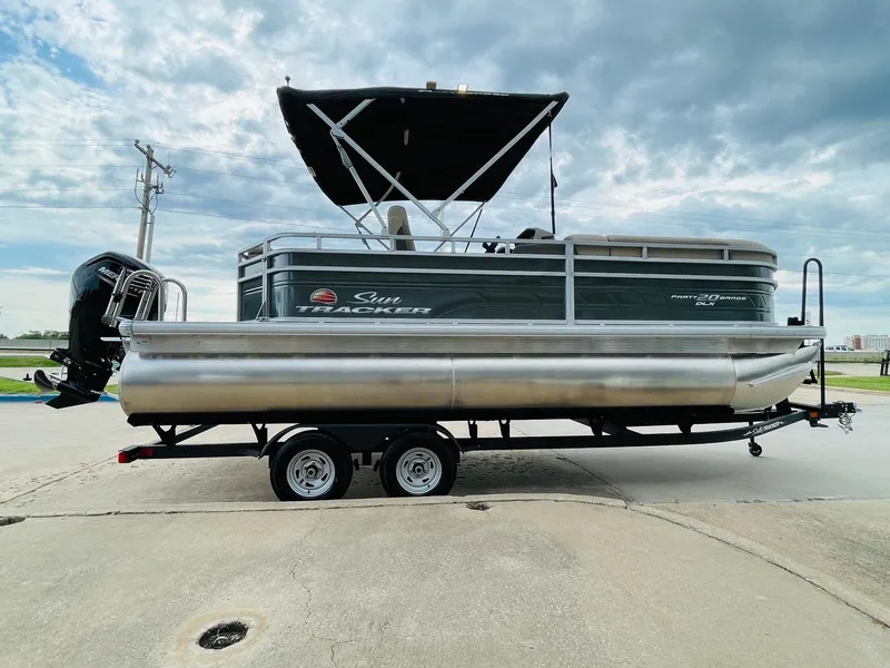 Slide: The Image of 2025 Sun Tracker Party Barge 20 DLX pontoon boat on trailer, under cloudy sky. - 4