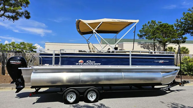 The Image of 2025 Sun Tracker Fishin' Barge 22 XP3 pontoon boat with canopy on trailer. - 0